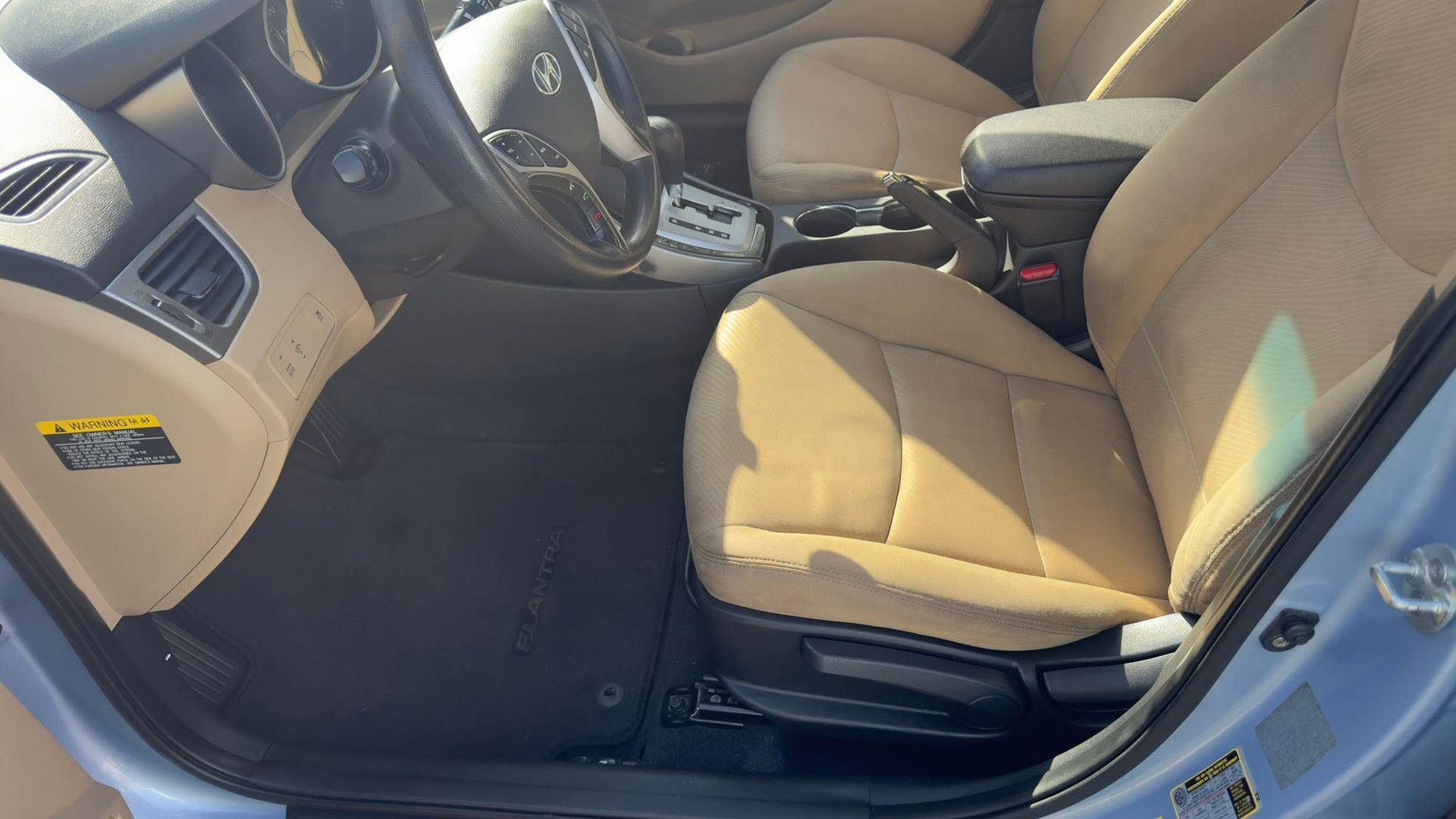 Tan interior of a car’s front seats and dashboard with the driver’s door open.