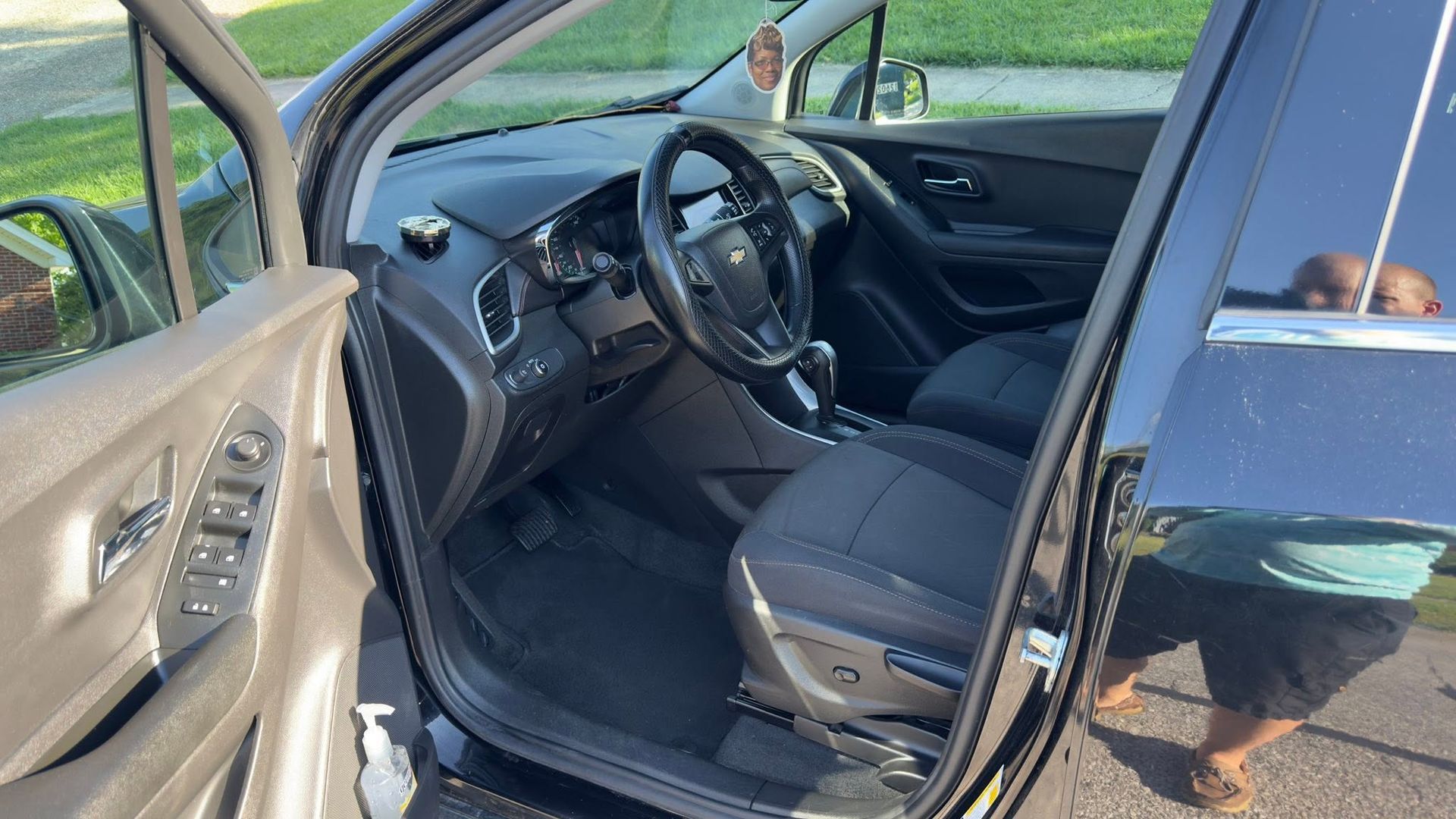 Open car with black interior, front driver’s seat visible and door ajar in daylight.