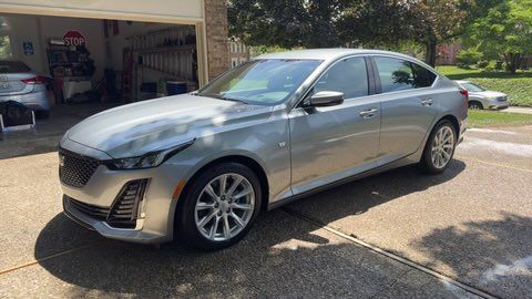 Silver sedan parked in a driveway beside an open garage on a sunny day