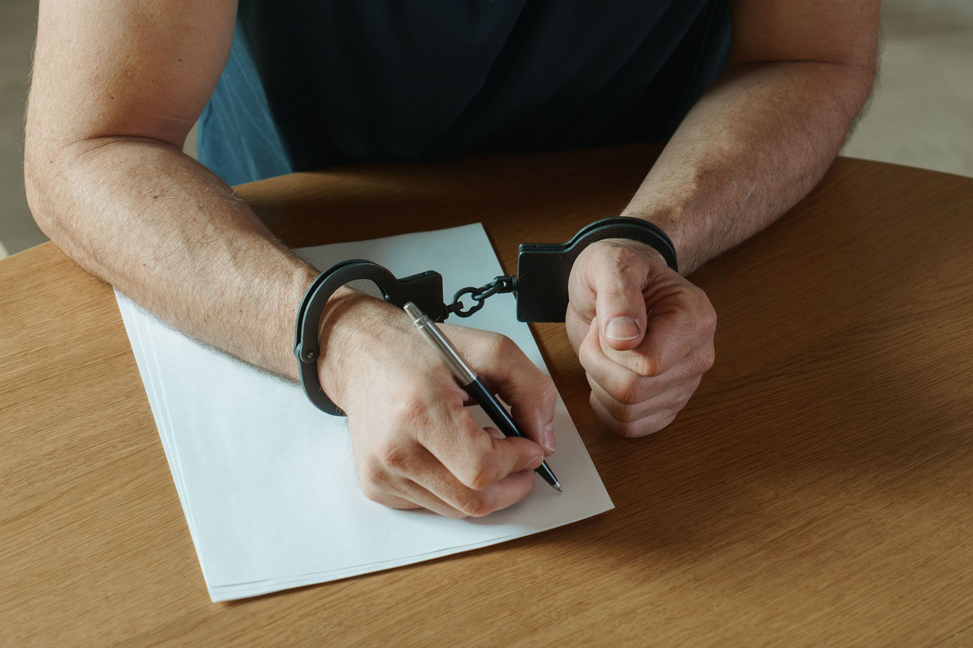 Man in Handcuffs Signing Document in Houston, TX
