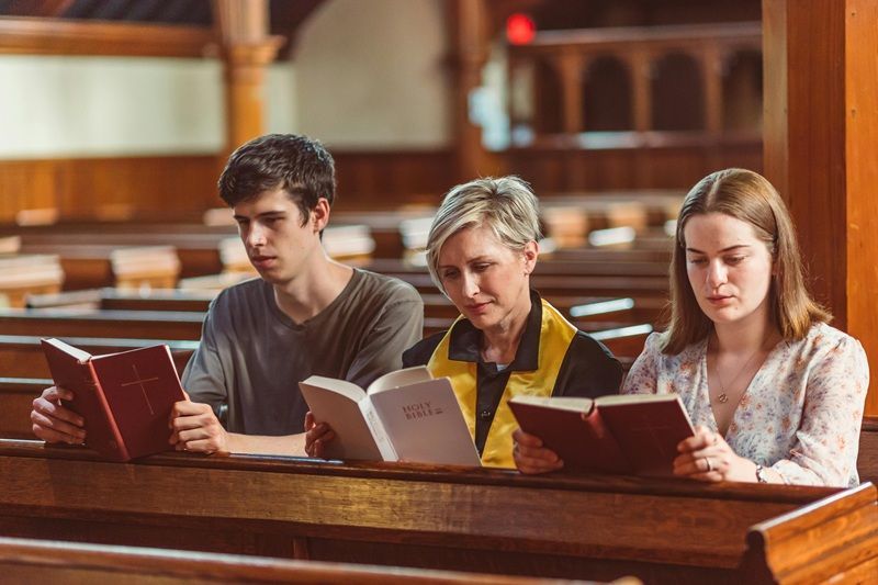 A group of people are reading books in a church.