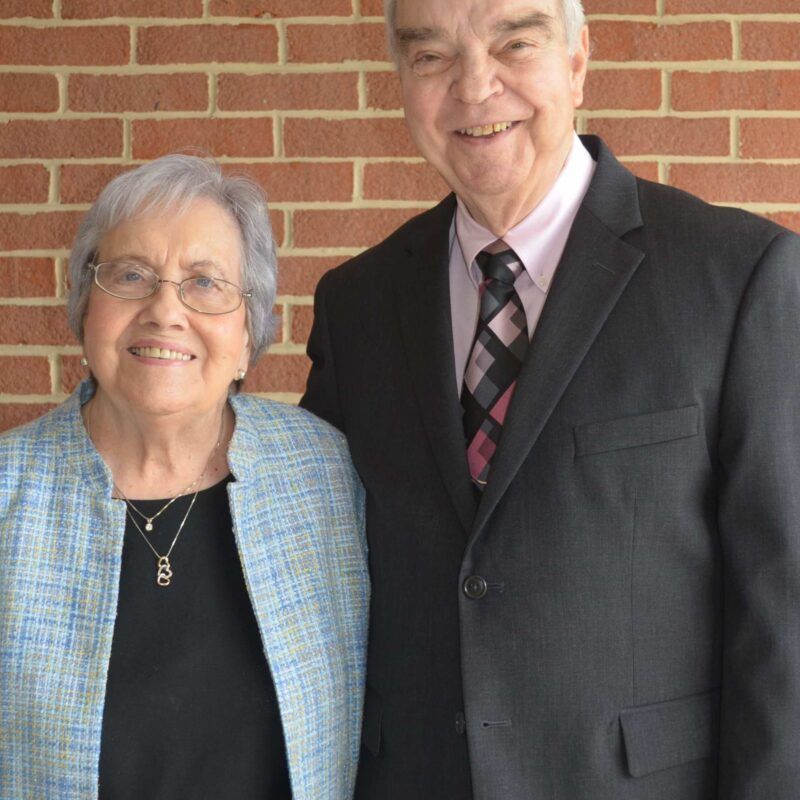 A man and woman are posing for a picture in front of a brick wall
