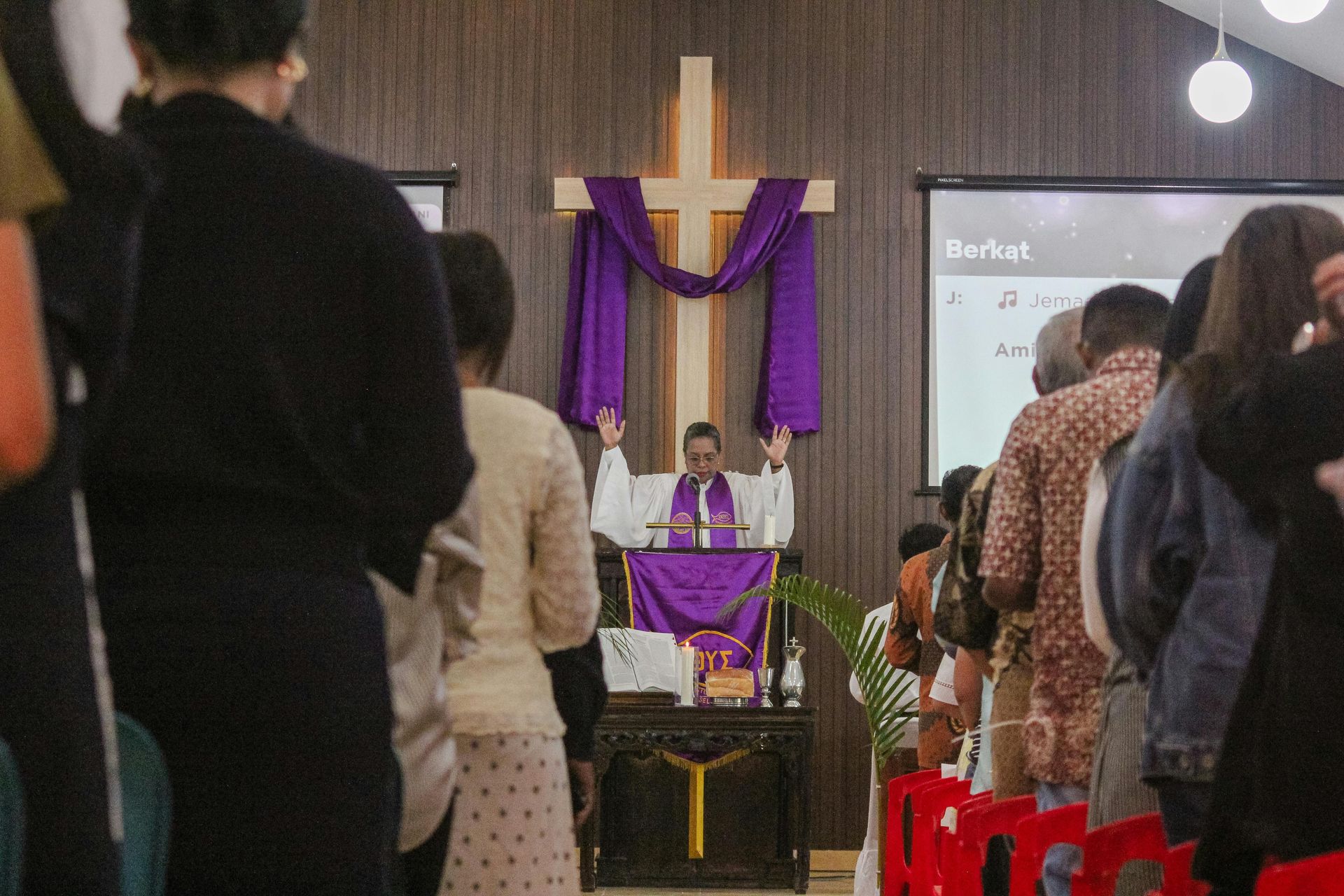 A man is giving a sermon in front of a crowd of people in a church.
