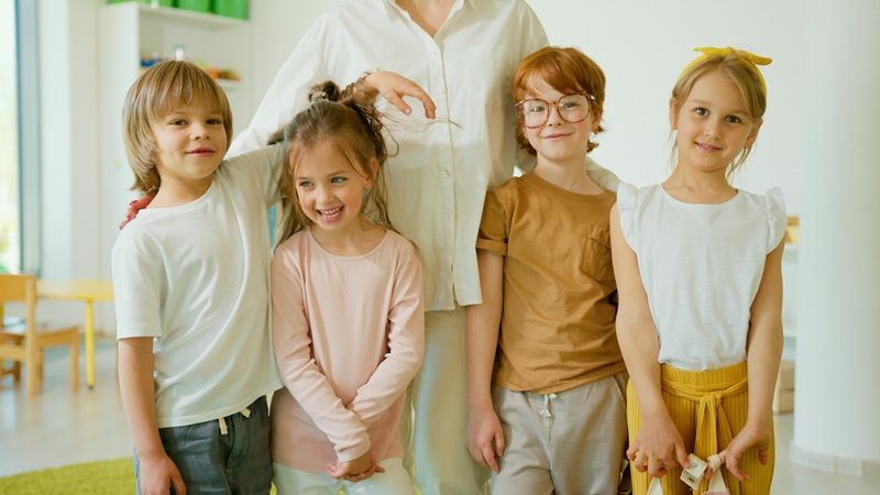 A group of children are posing for a picture with their teacher.