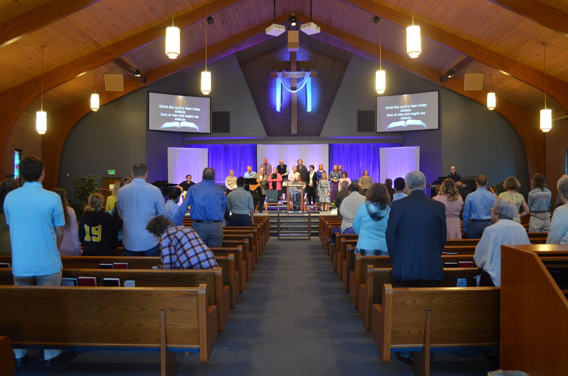 A large group of people are sitting in a church watching a service.