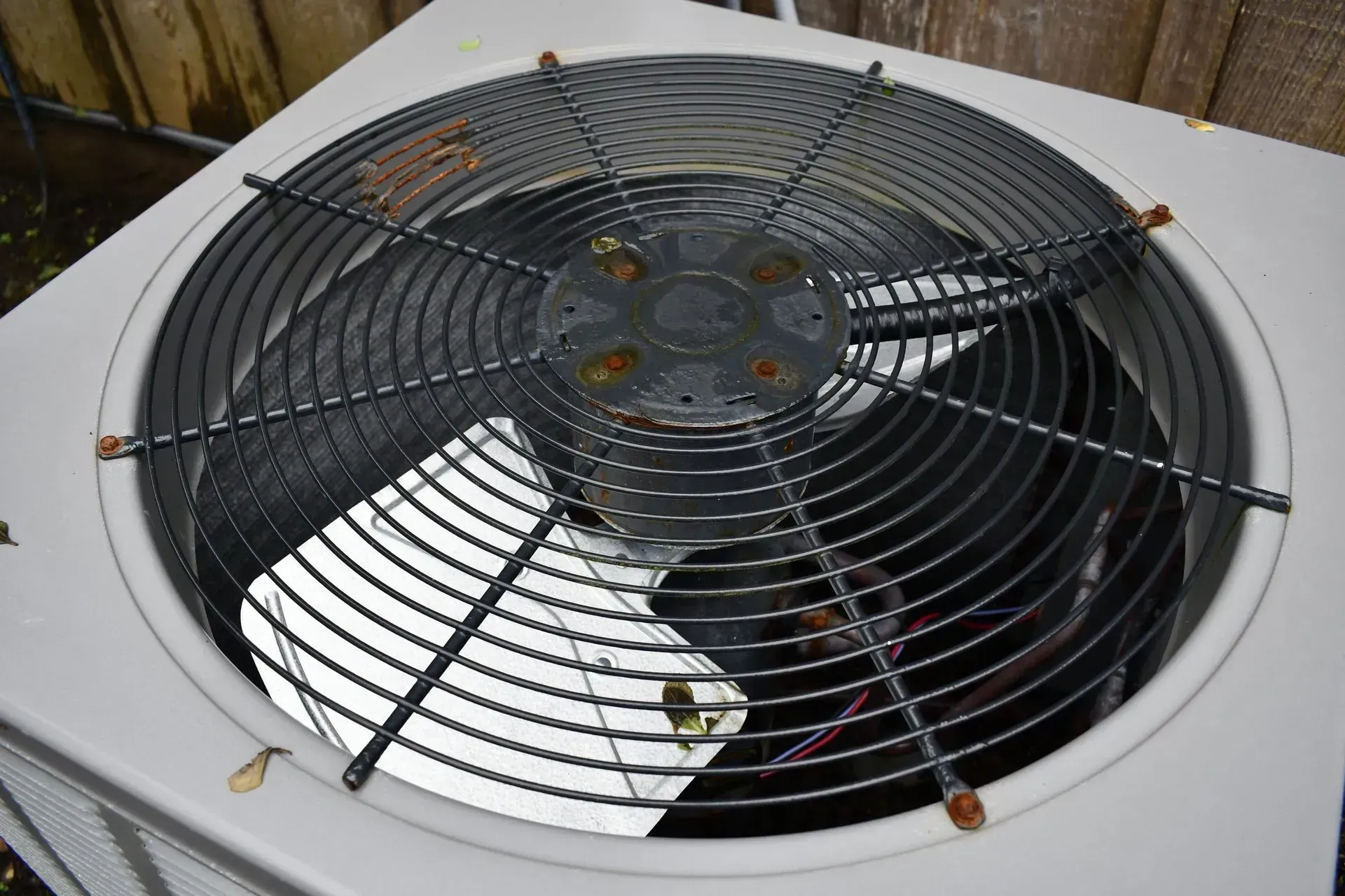 Top view of a white outdoor air conditioning unit with a black fan grille