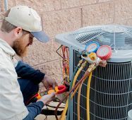HVAC technician using gauges to service an outdoor air conditioner unit