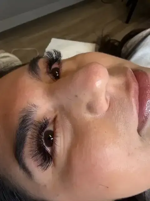 Close-up of a person's face lying sideways, showing long eyelashes and glossy lips.