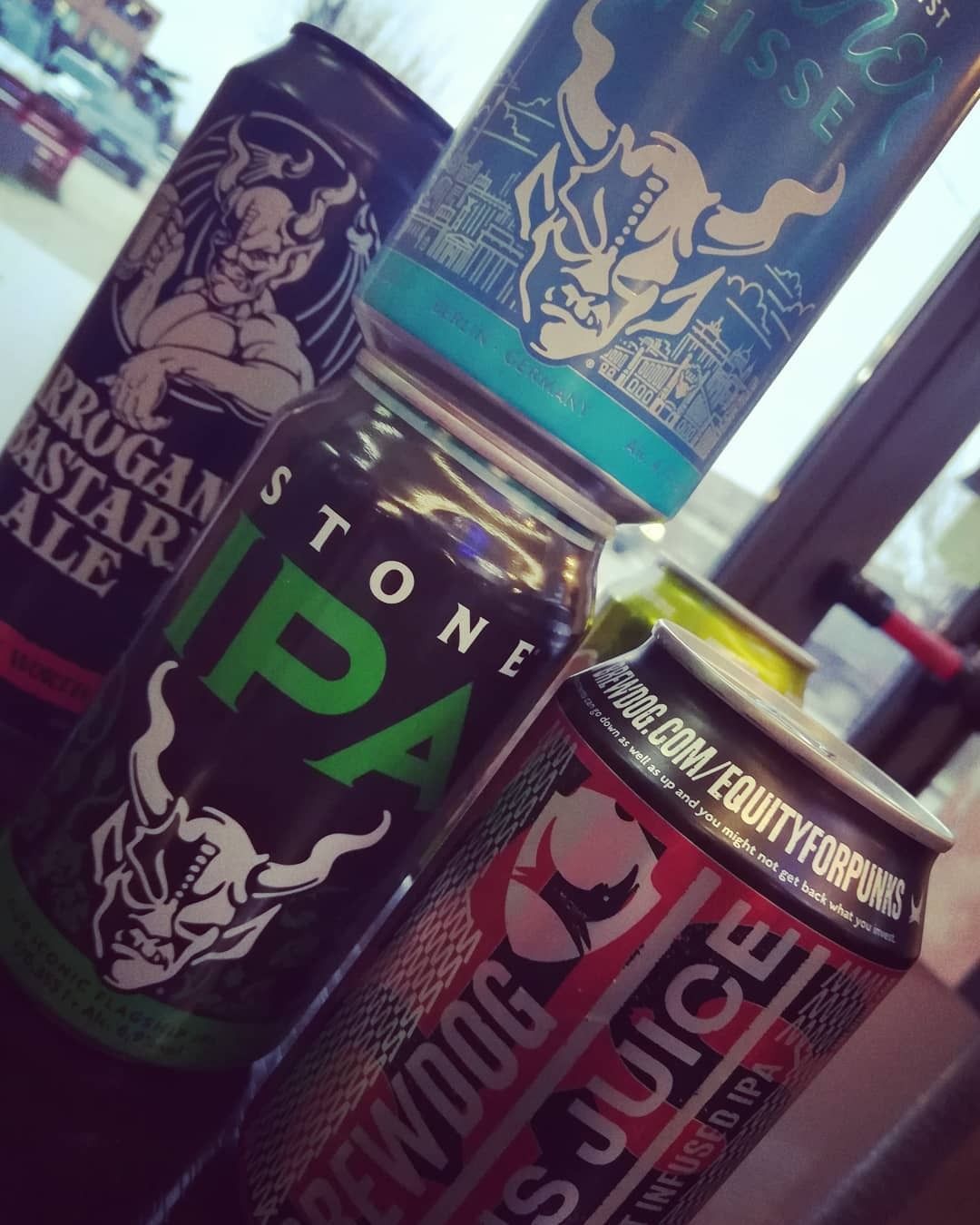 Quattro lattine di birra impilate: Stone IPA, Brewdog e due con il logo del diavolo.