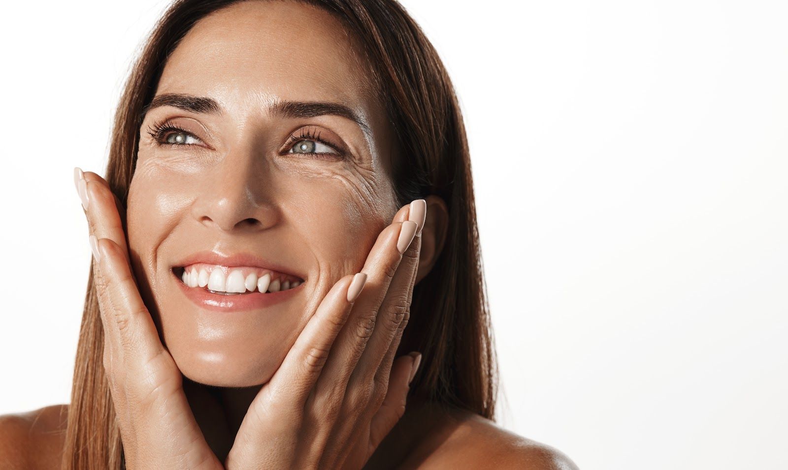 Smiling woman gently touching her cheeks on a white background