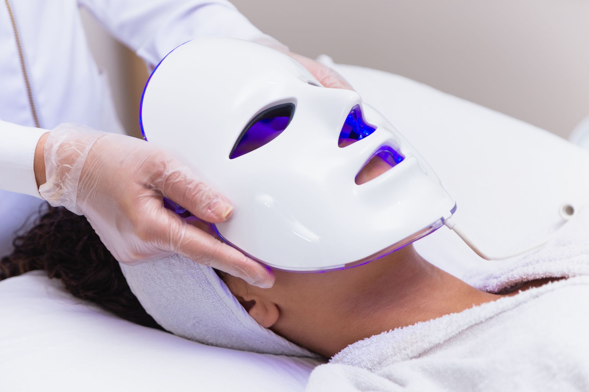 A woman is getting a facial treatment with a mask on her face.