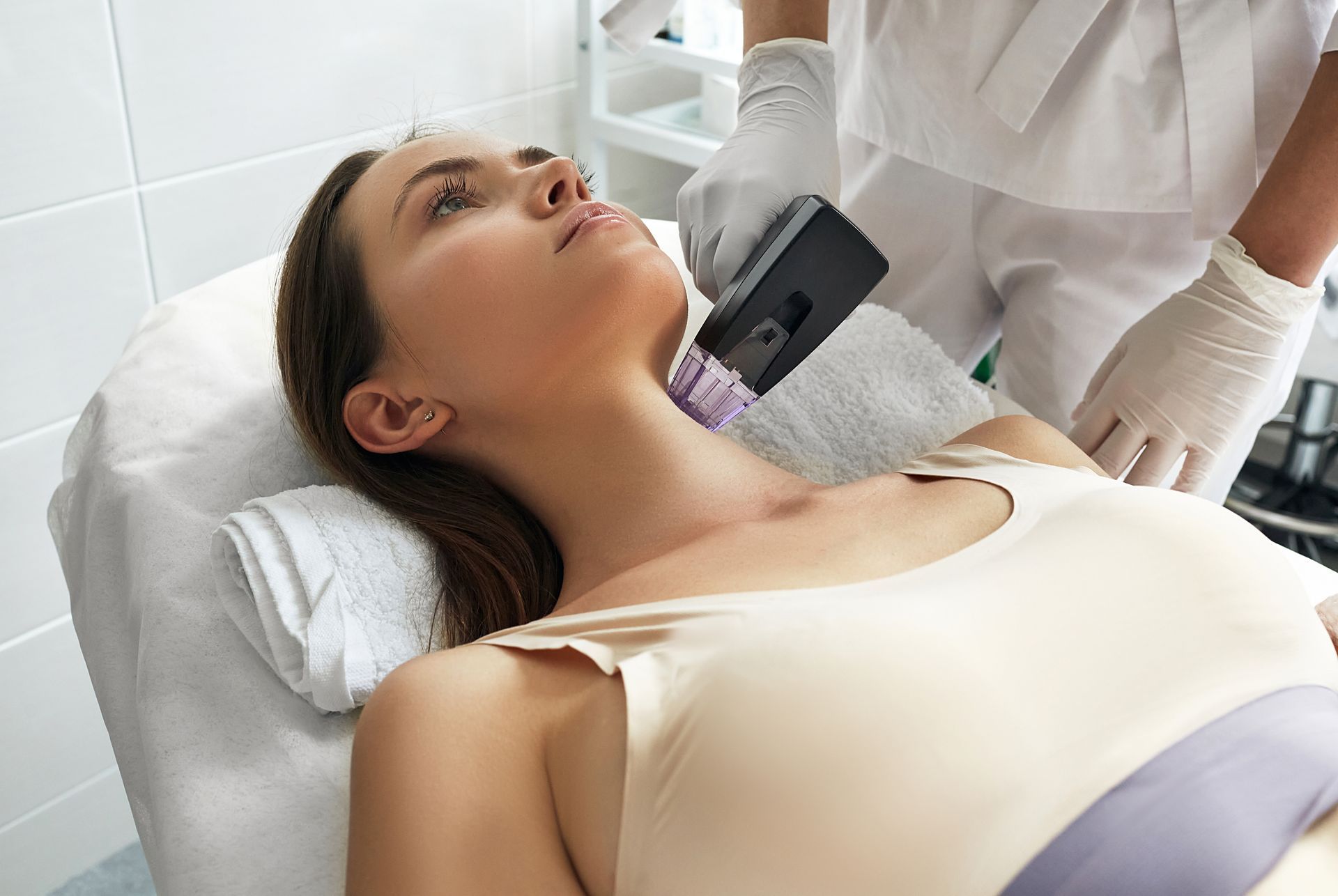 A woman is laying on a bed getting a laser treatment on her face.