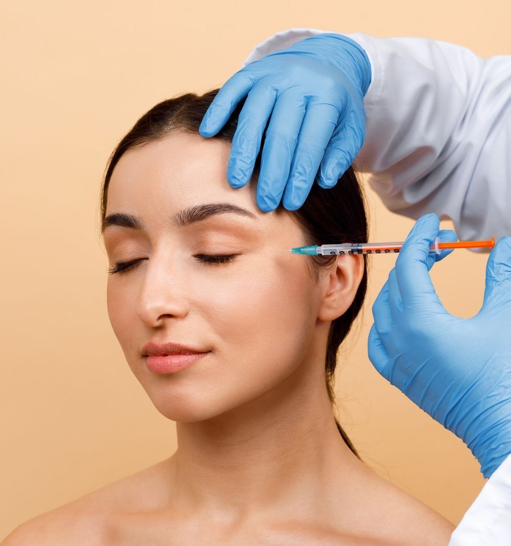 A woman is getting a botox injection in her forehead.