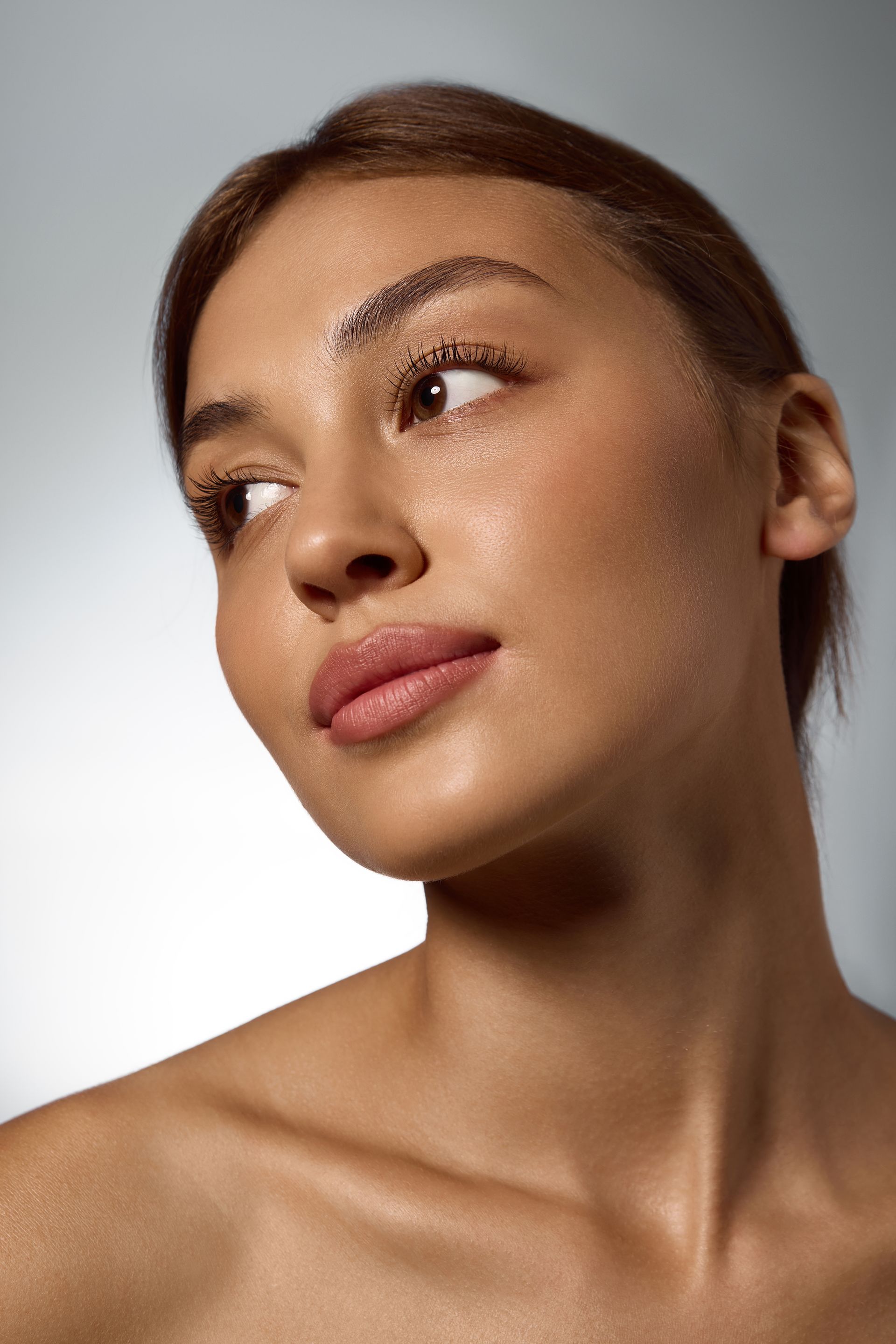 Portrait of a person looking up and to the side against a gray background