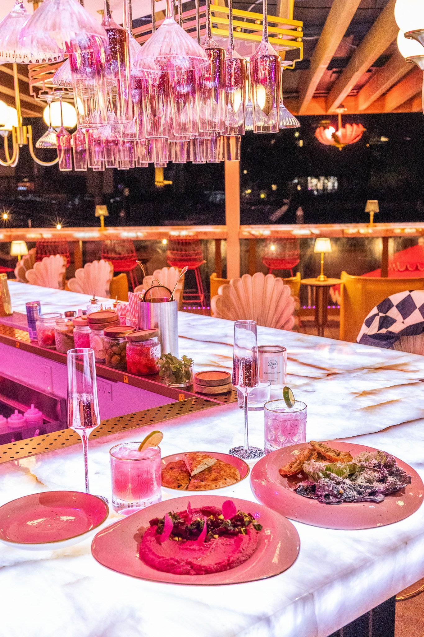 Banquet table with pink tableware and hanging floral decor in a warmly lit restaurant