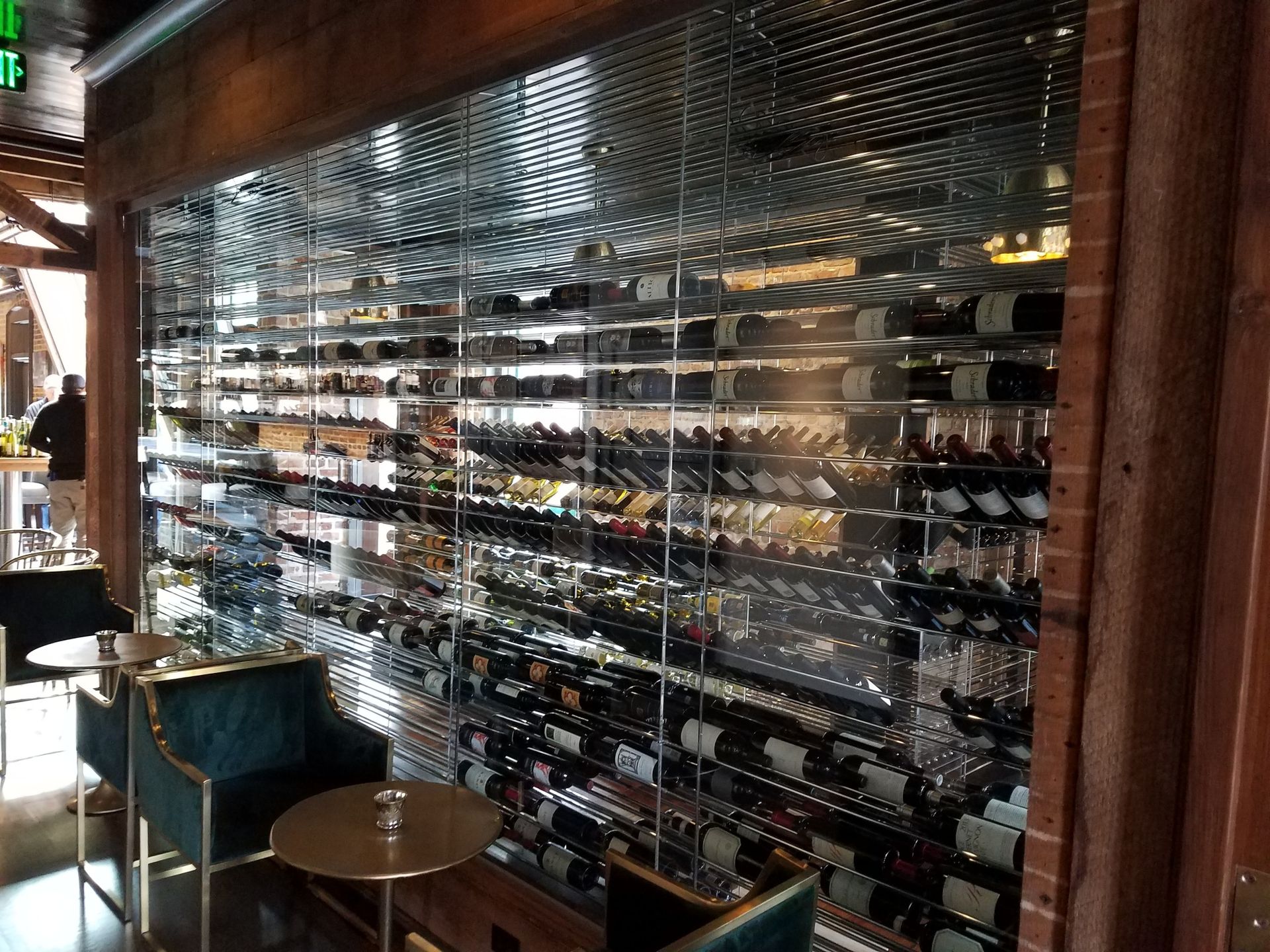 Wine display inside a restaurant with rows of bottles and mirrored shelves