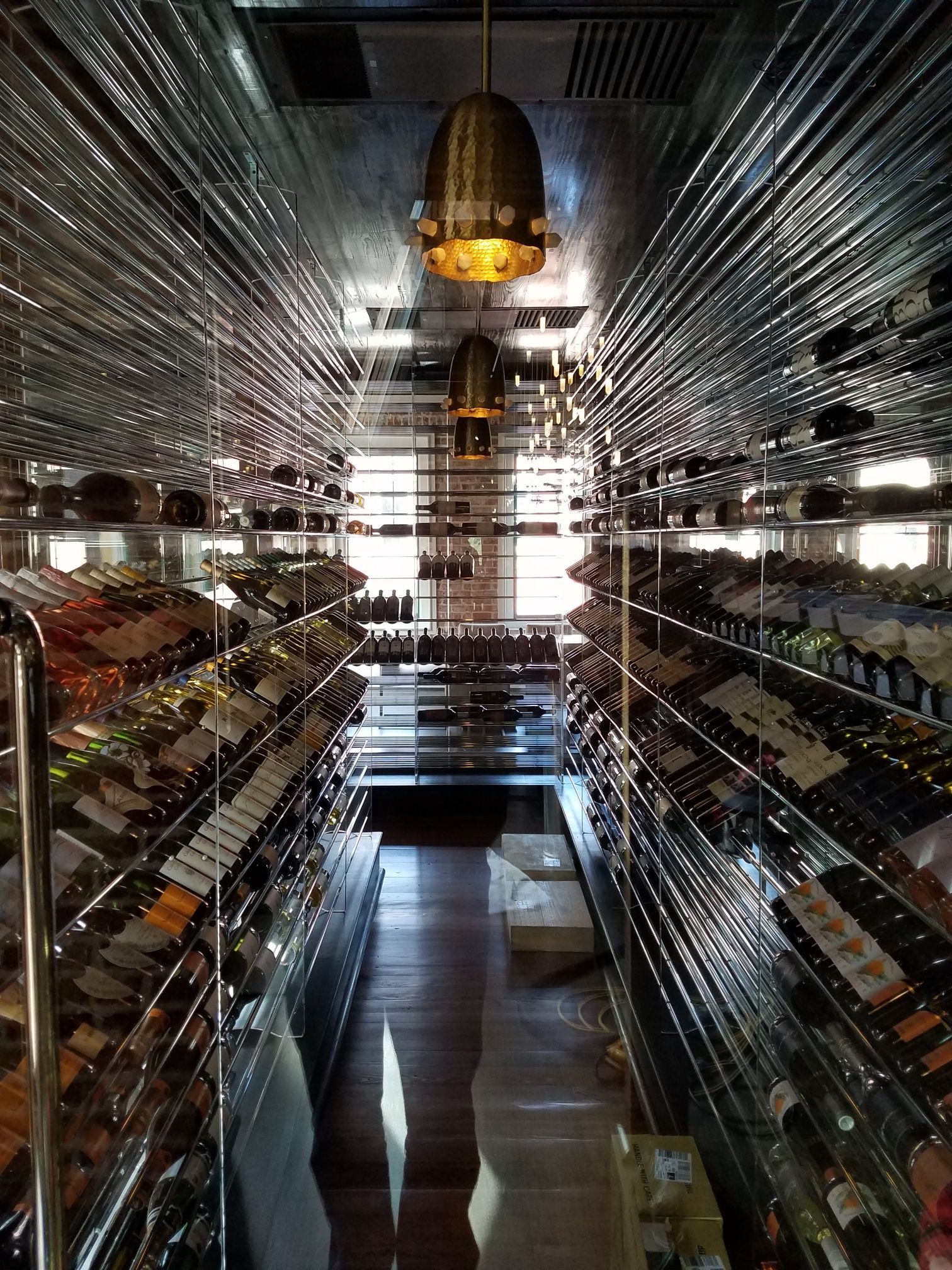 Mirrored hallway with rows of shelves and a glowing chandelier reflected on polished floor