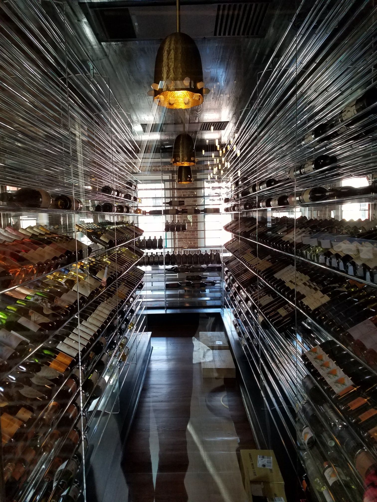 Interior of a mirrored chamber with a central golden hanging fixture and rows of reflective surfaces on both sides