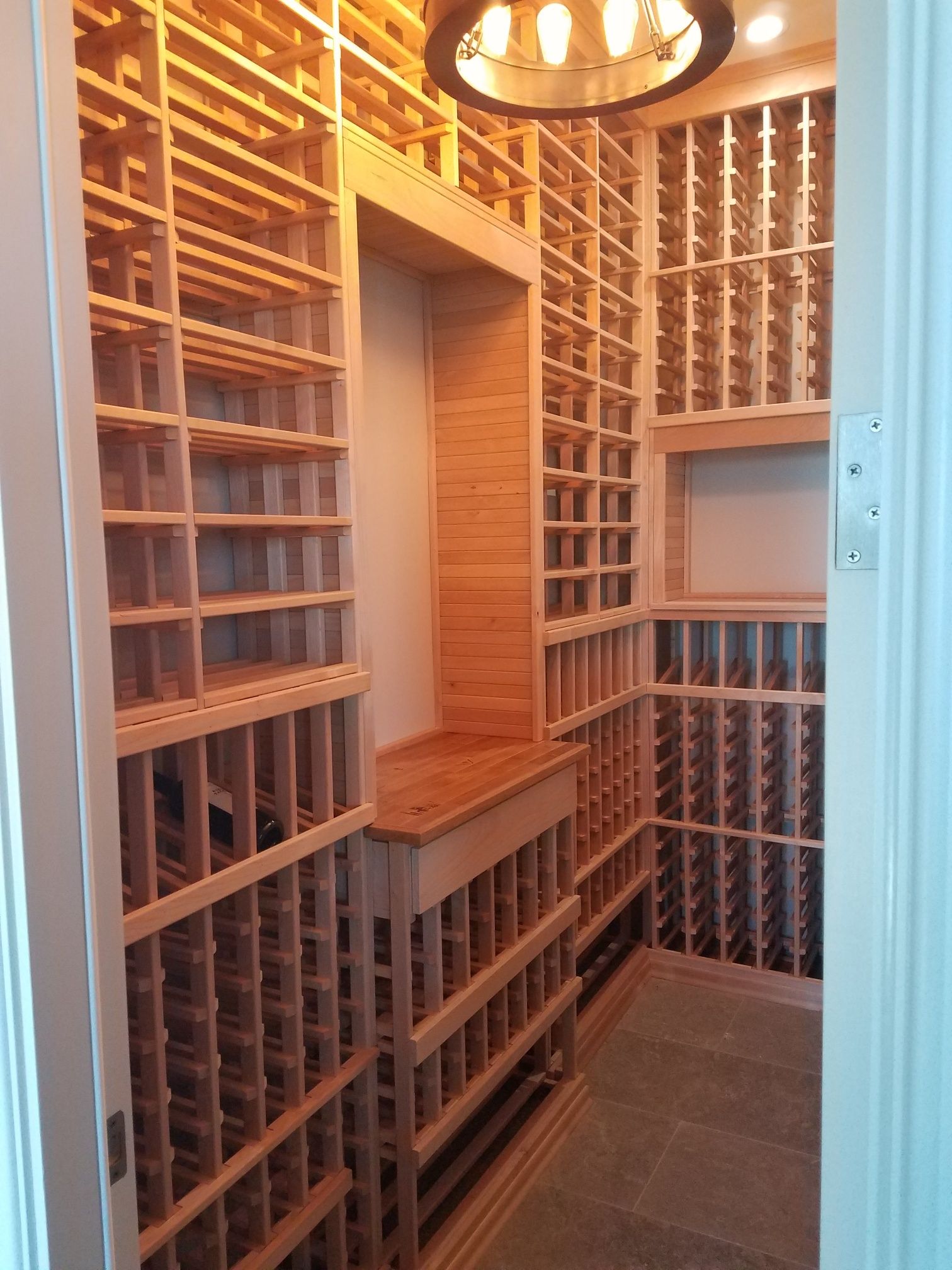 Narrow wood-paneled closet with built-in shelving, drawers, and warm ceiling light.