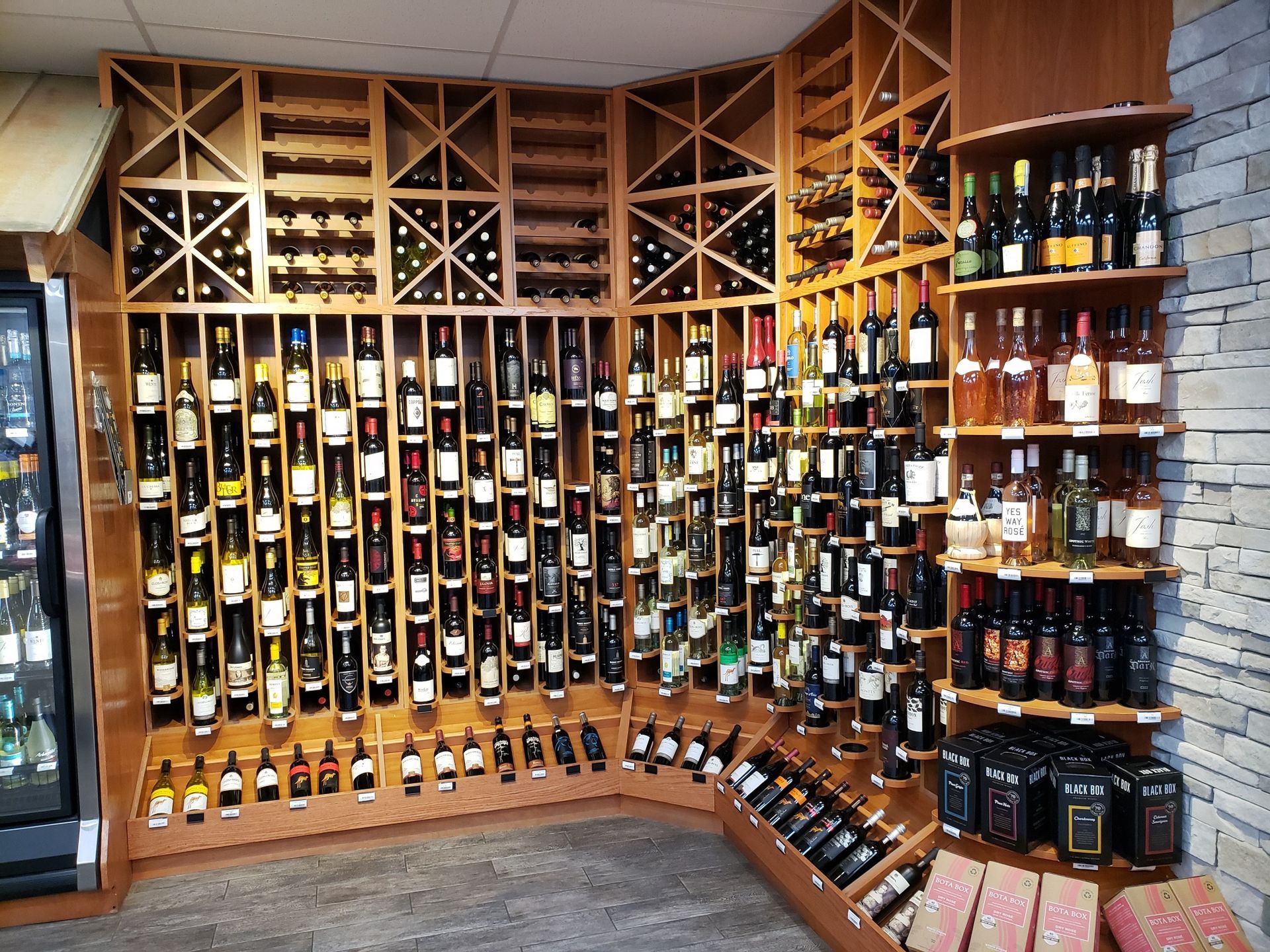 Wine bottles displayed on curved wooden shelves in a liquor store