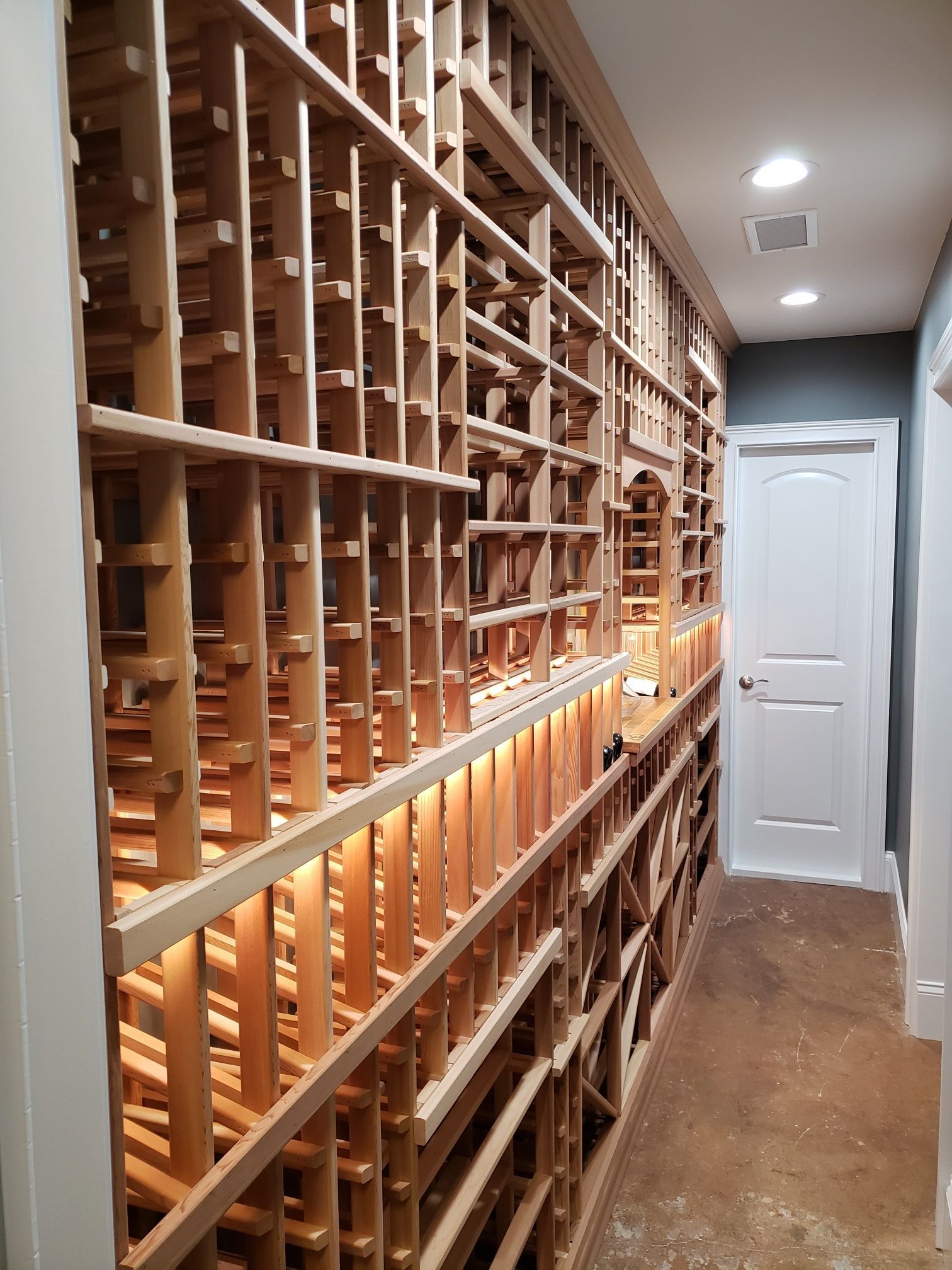 Narrow hallway lined with wooden cubby shelves and a white door at the end