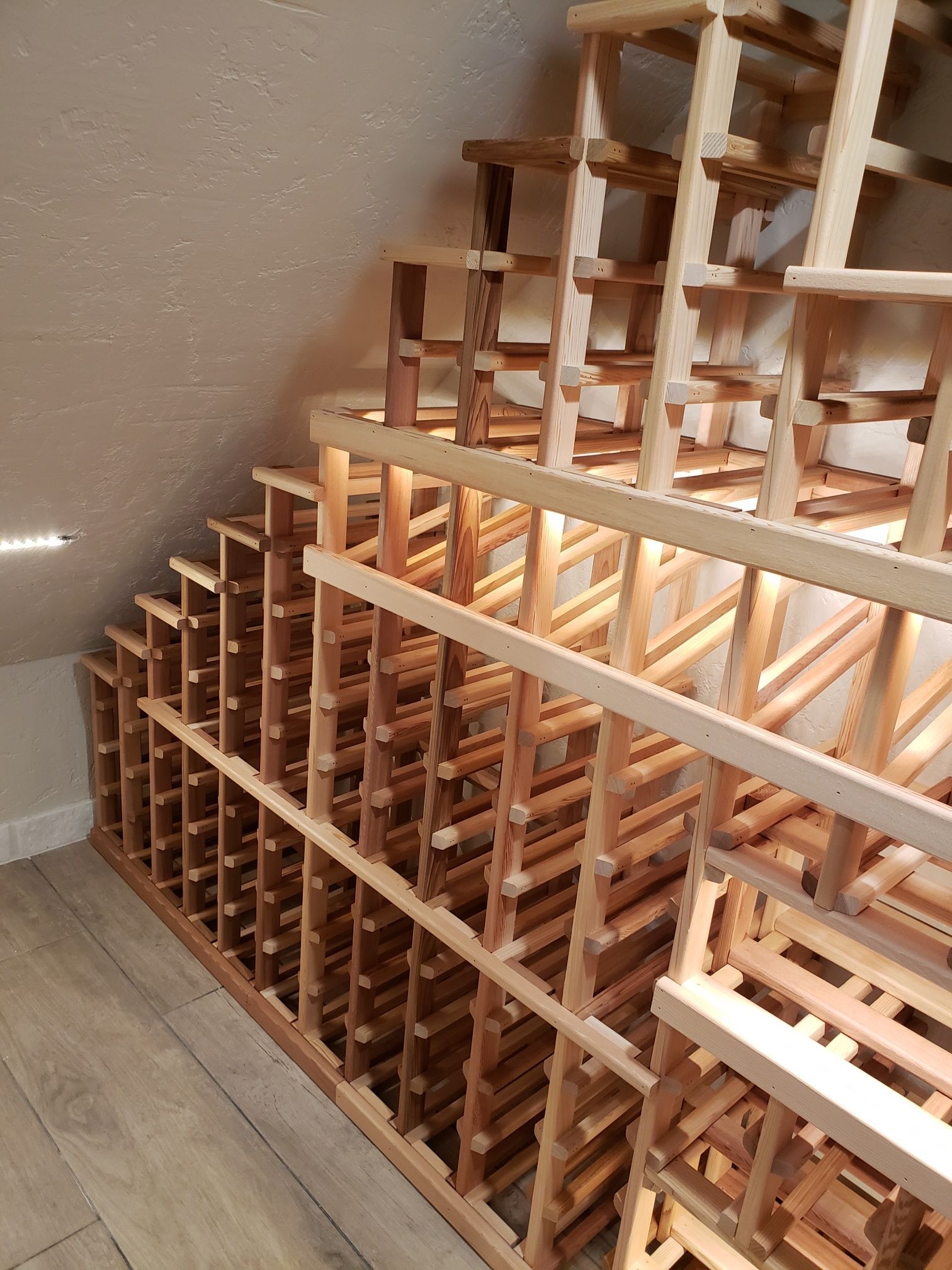 Unfinished wooden storage racks in an attic with a sloped ceiling and light wood floor