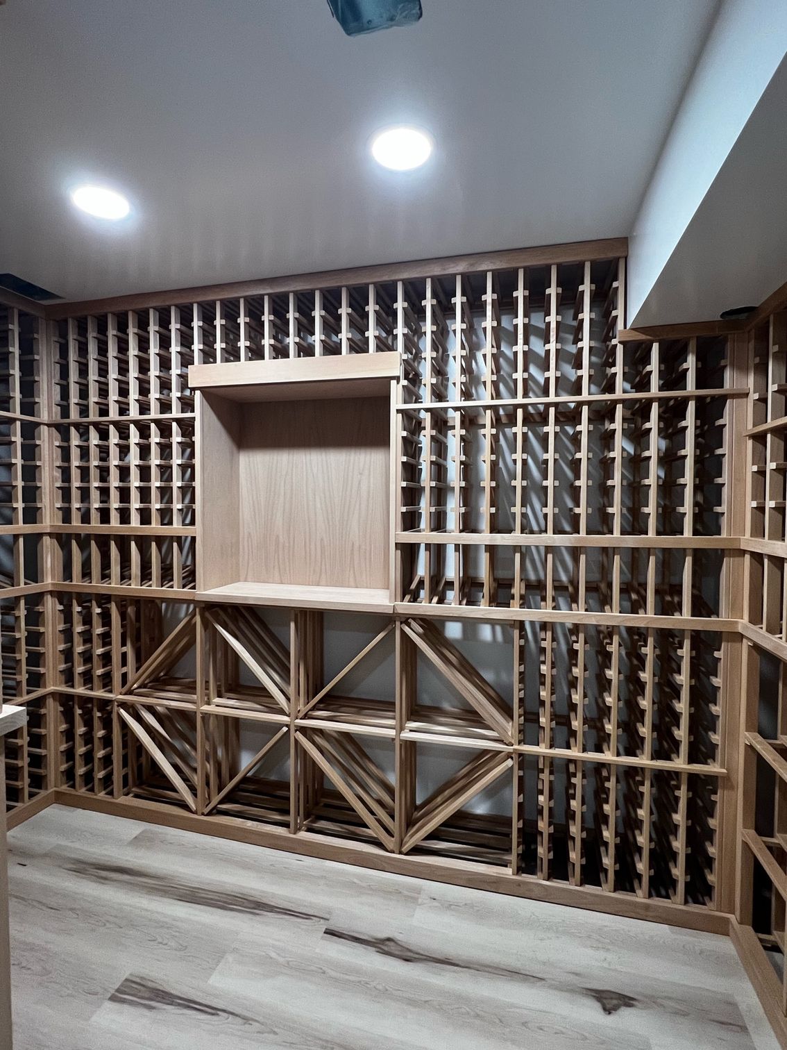 Empty room with decorative wooden lattice wall, recessed shelf, and gray wood-pattern flooring under ceiling lights