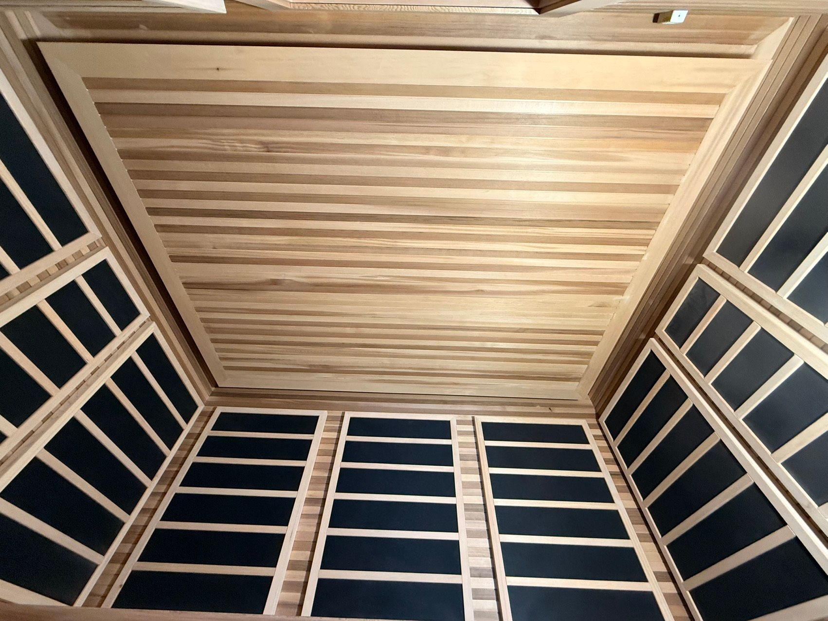 Wooden room interior with slatted ceiling and dark blue paneled walls.