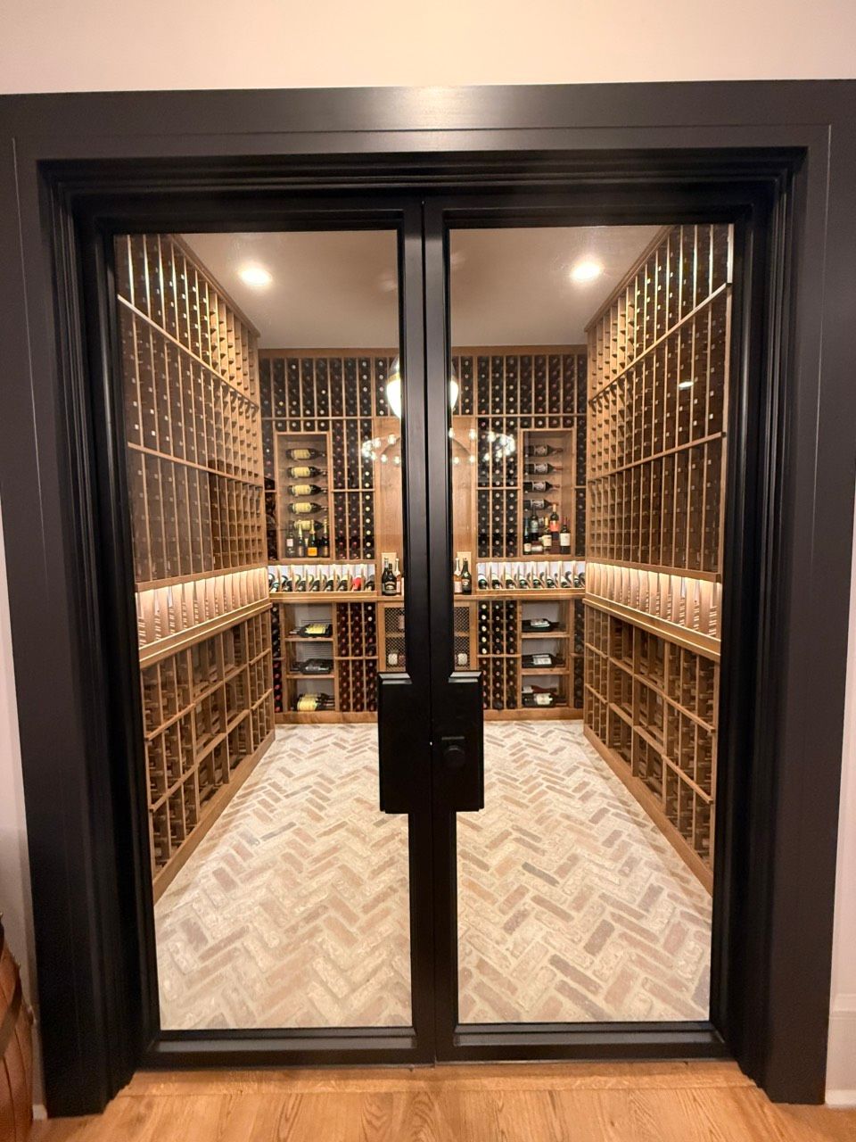 Elegant wine cellar with floor-to-ceiling wooden racks and glass double doors