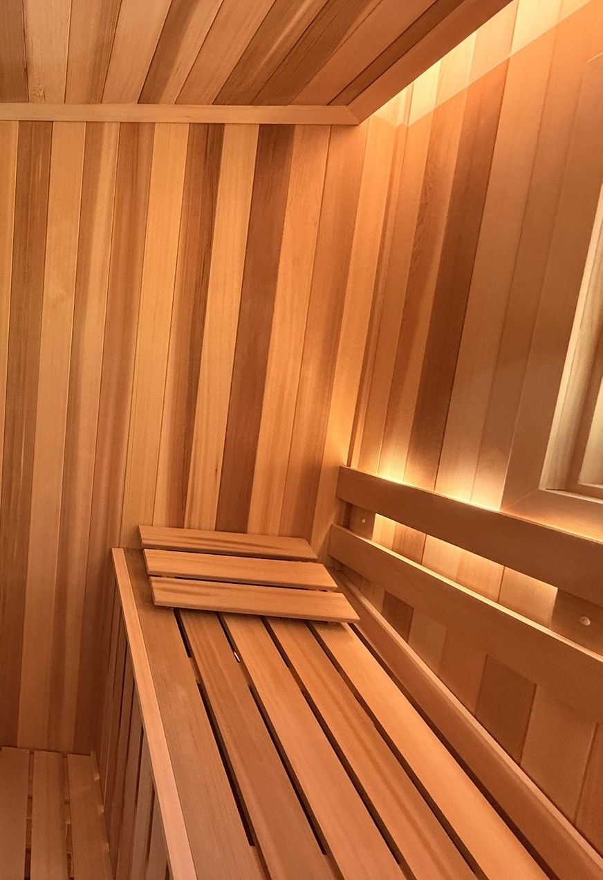 Wooden sauna interior with slatted bench and warm amber lighting