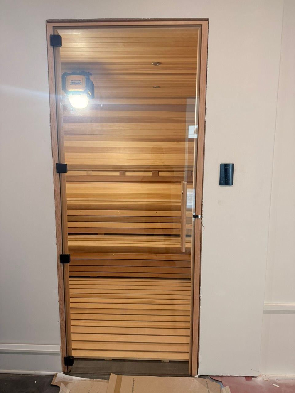 Wooden door with frosted glass panels and a lit porch light on a white wall