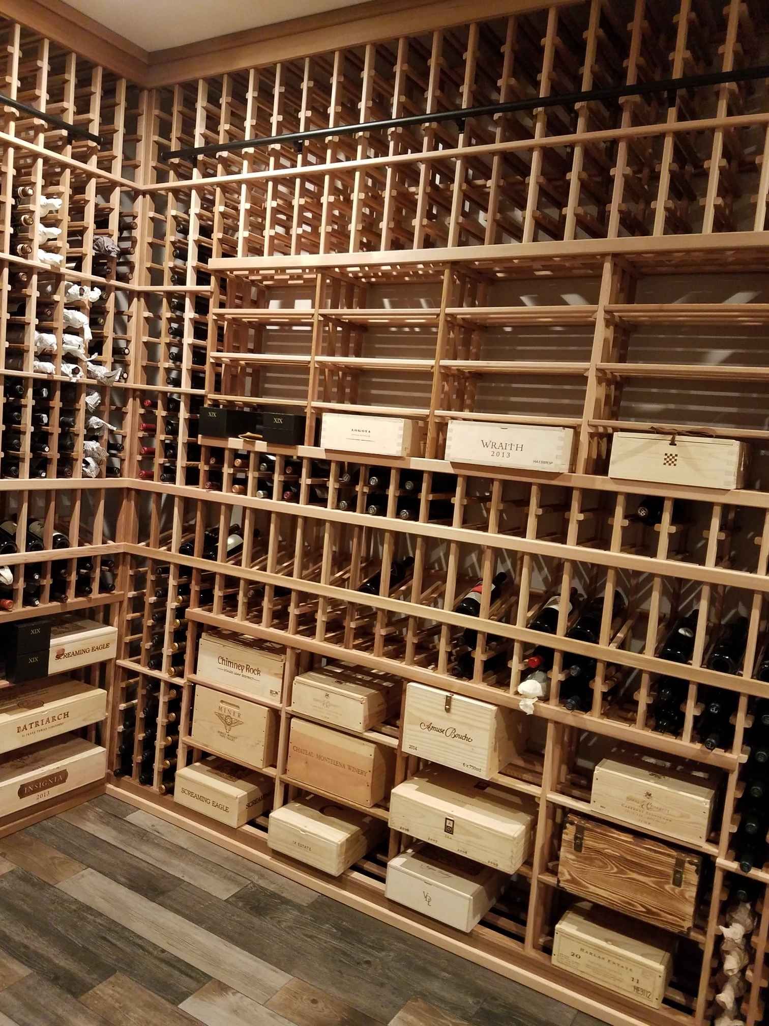 Wooden wine rack filled with many bottles and storage boxes in a cellar