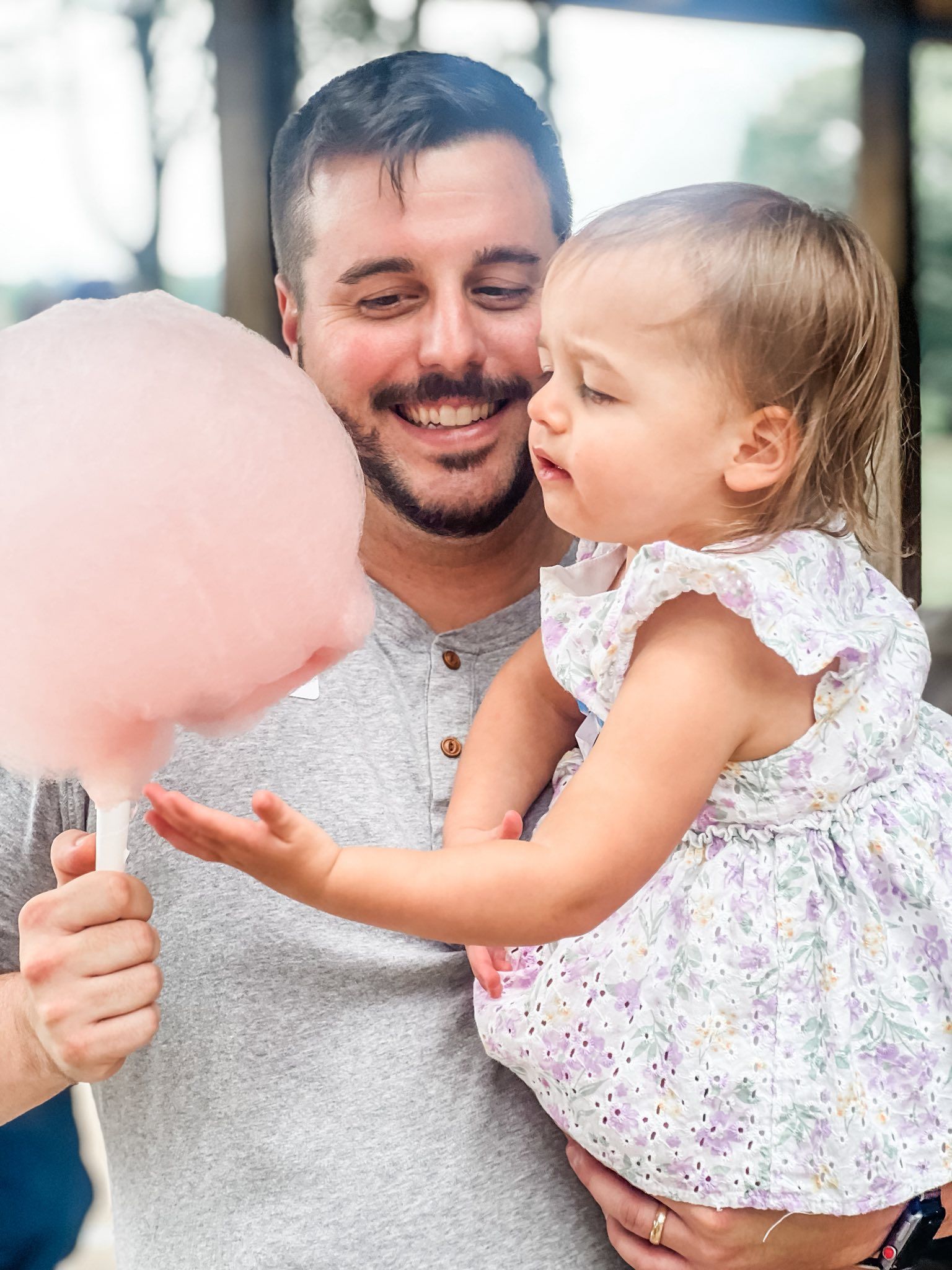 Man holding a cotton candy, looking at toddler at Healing Journey Foundation picnic.