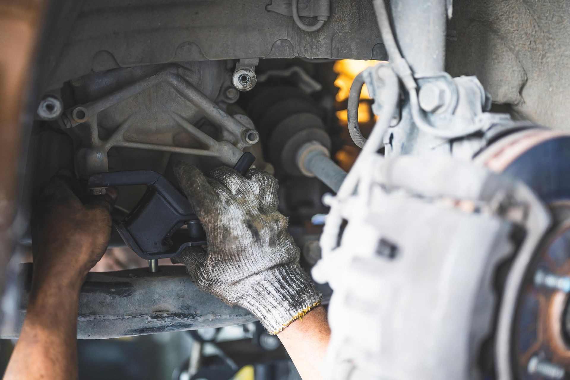 Mechanic working on a car’s wheel hub and suspension inside a garage