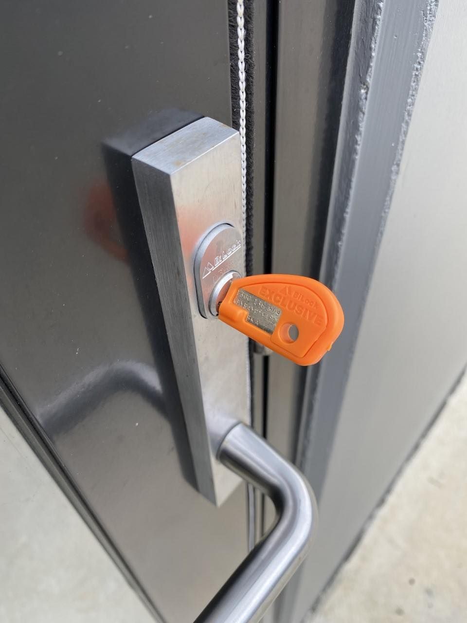A Close Up Of A Door With An Orange Key On It — KeyBay in Macarthur, NSW