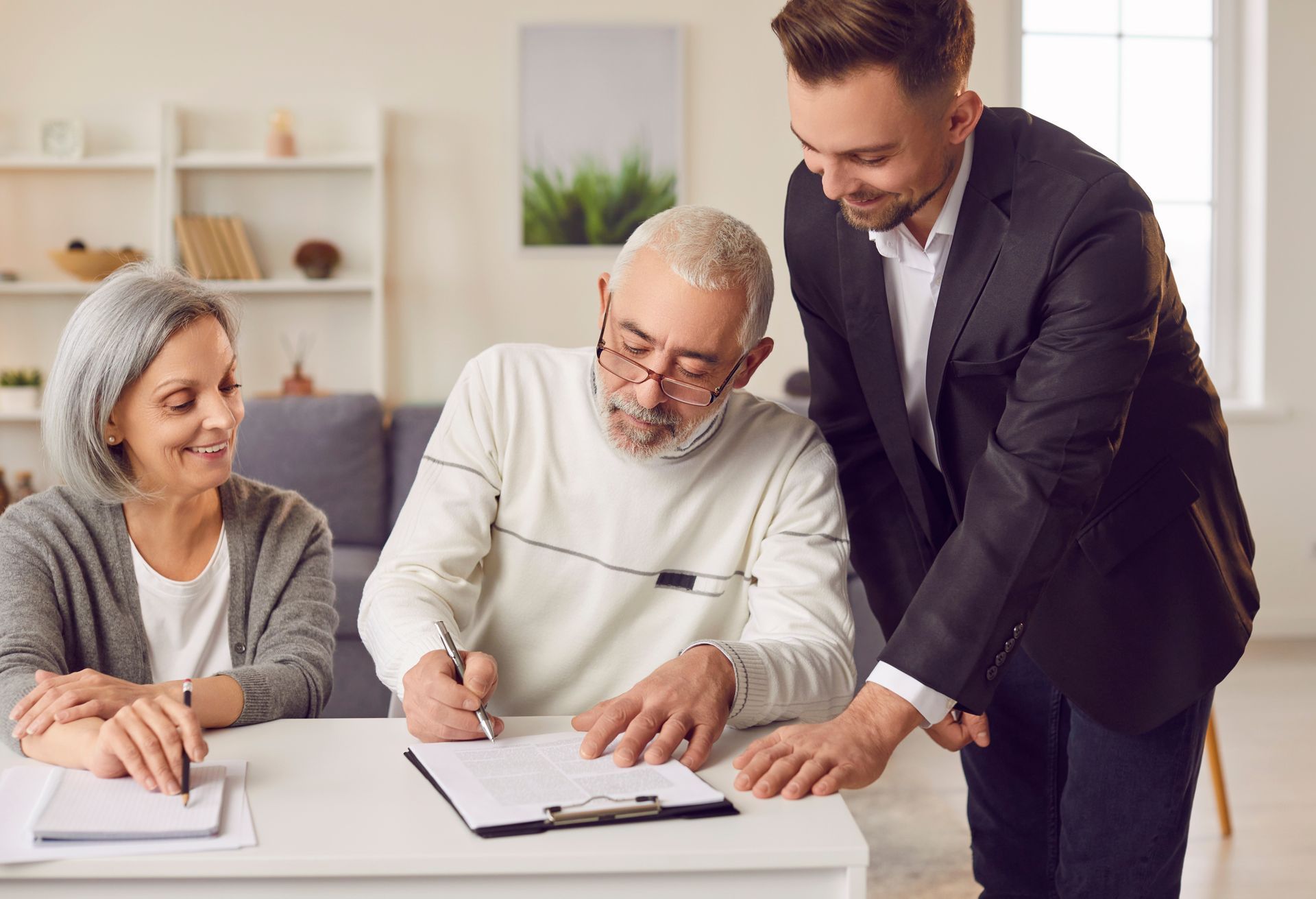 Three people collaborate at a table, reviewing papers in a bright office.