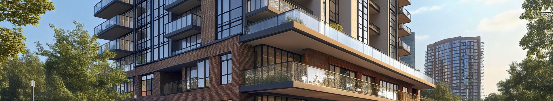 Modern apartment building with balconies and brick facade beside trees in warm sunlight