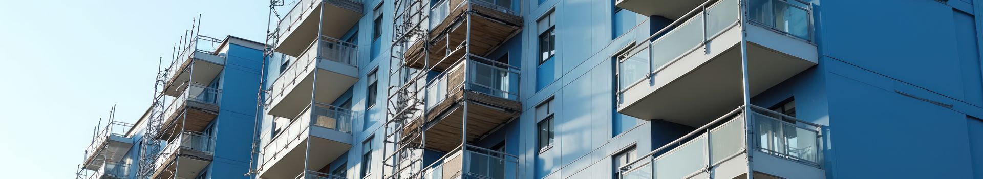 Apartment building balconies with blue walls and orange railings under construction