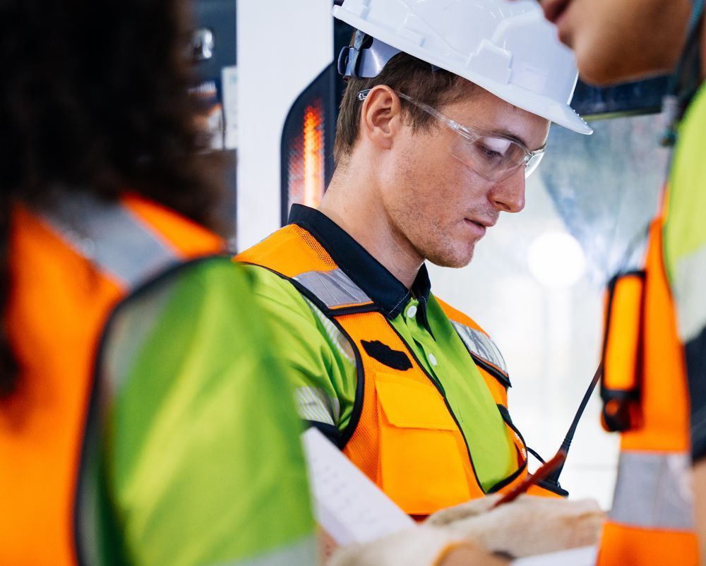 Worker in hard hat and safety vest reviewing plans at a construction site