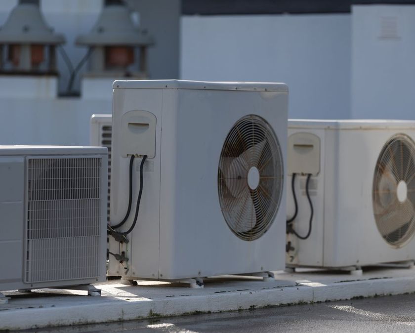 Row of rooftop air conditioning units with fans and metal casings