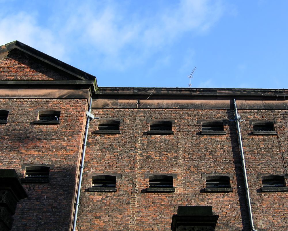 Old brick warehouse facade with small windows under a blue sky