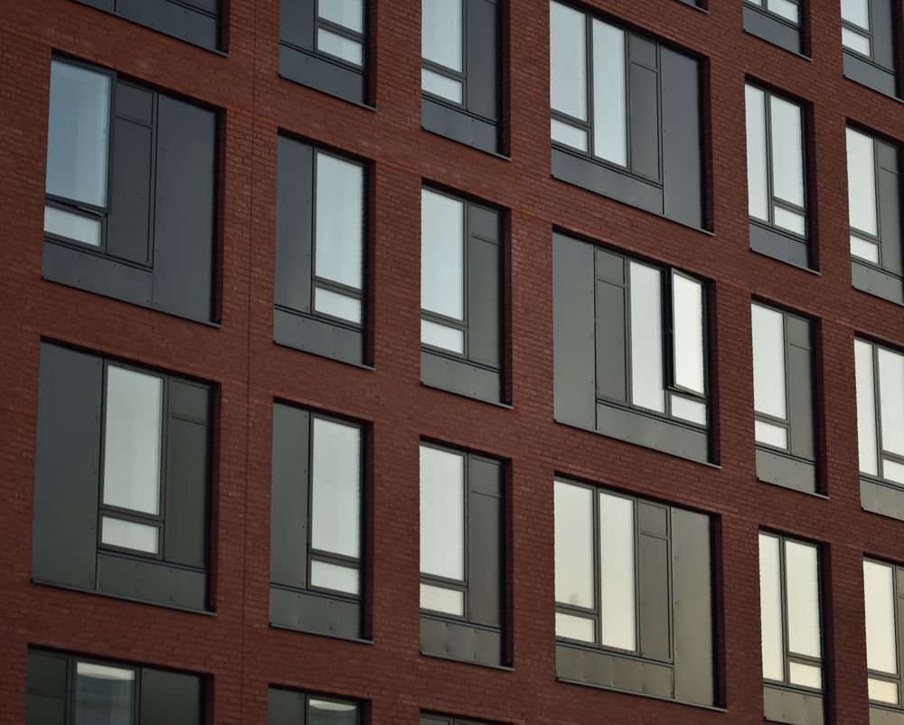 Brick apartment building facade with rows of dark-framed windows