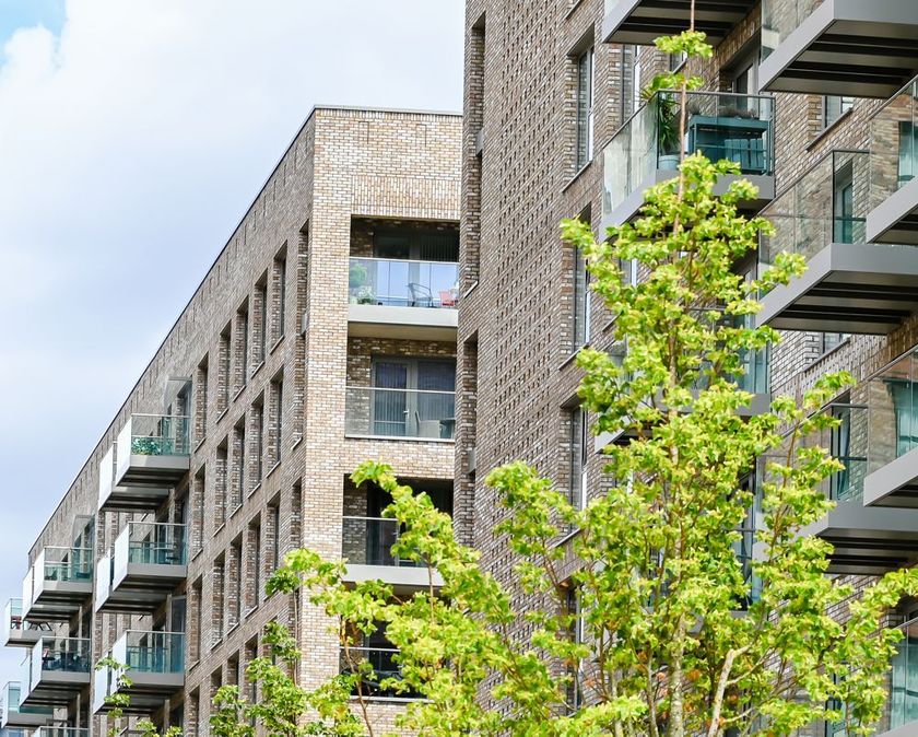 Modern apartment buildings with glass balconies and green trees in front