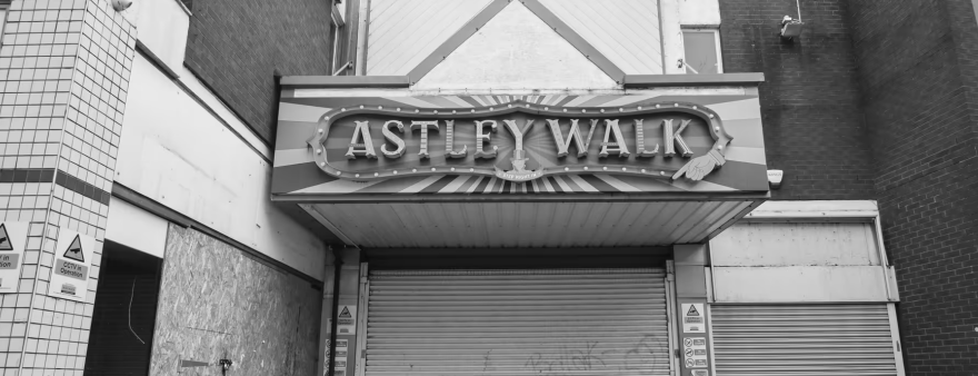 Black-and-white storefront sign reading “ASHTEY WALK” above a closed shutter entrance