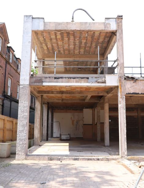 Partially built concrete structure with two open levels and scaffolding in an urban street.