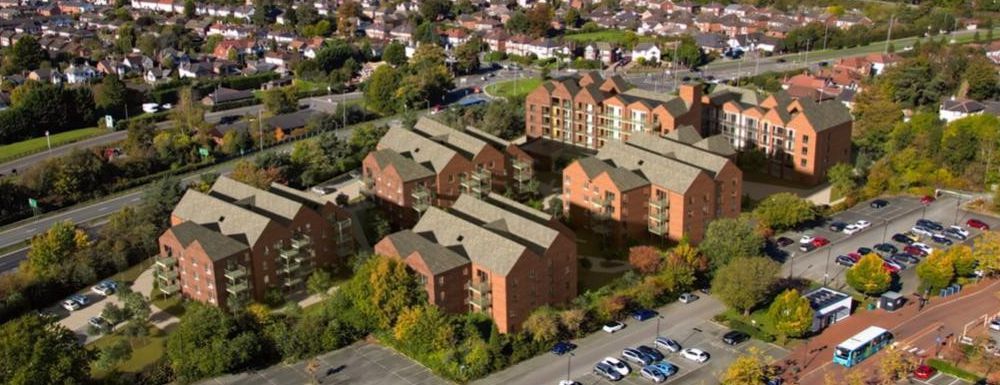 Aerial view of red-brick apartment buildings beside a parking lot in a leafy suburban neighborhood