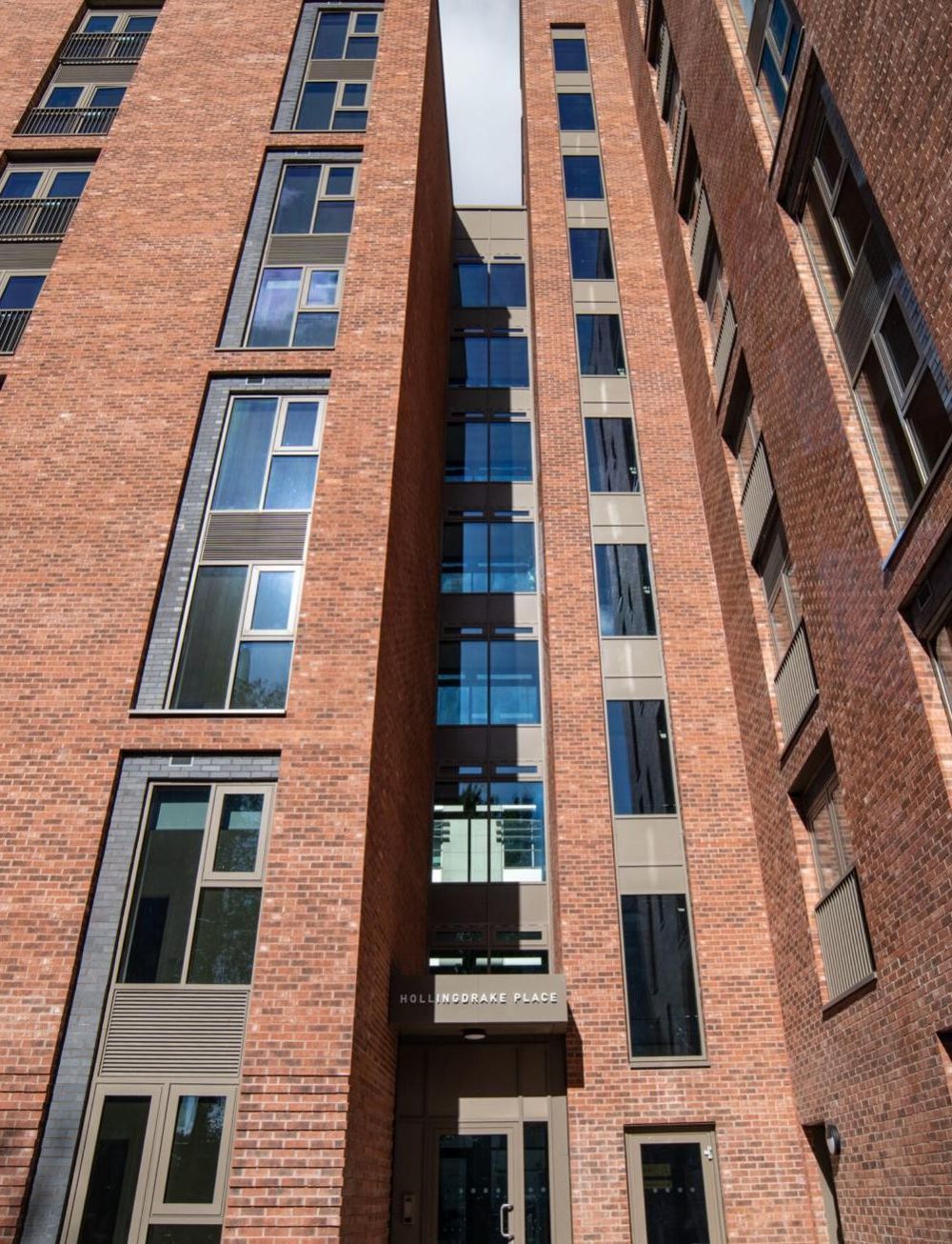 Tall brick apartment building with many windows against the sky
