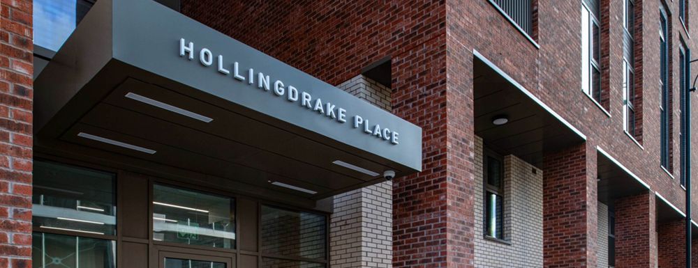 Brick building entrance with a black awning labeled “Hollingsworth Place”