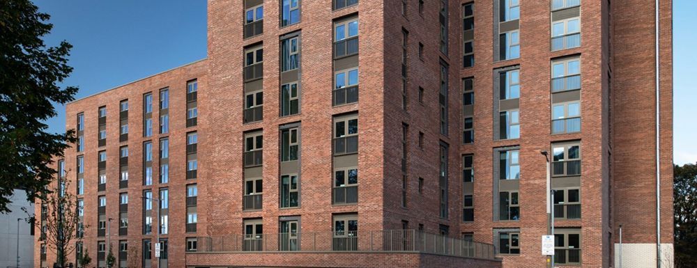 Brick apartment building with rows of windows under a blue sky