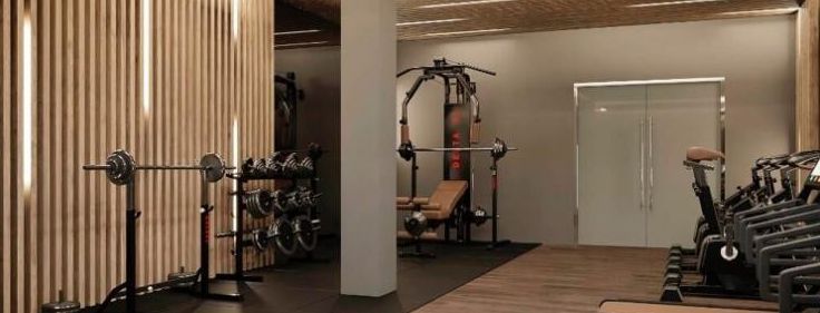 Empty gym with weight machines, a bench, and mirrored walls under warm lighting